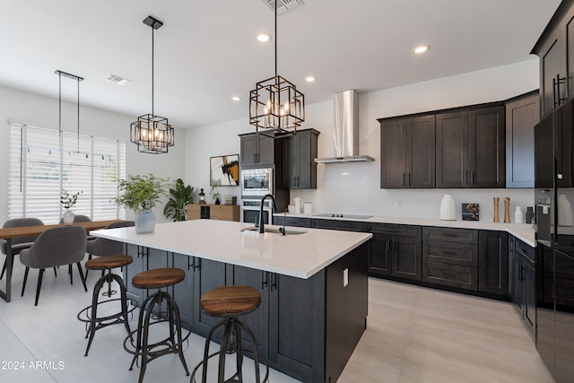 kitchen with stainless steel appliances, light tile patterned floors, decorative light fixtures, sink, and wall chimney exhaust hood