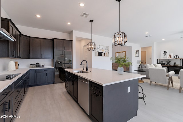 kitchen with dishwasher, an island with sink, hanging light fixtures, sink, and wall chimney range hood