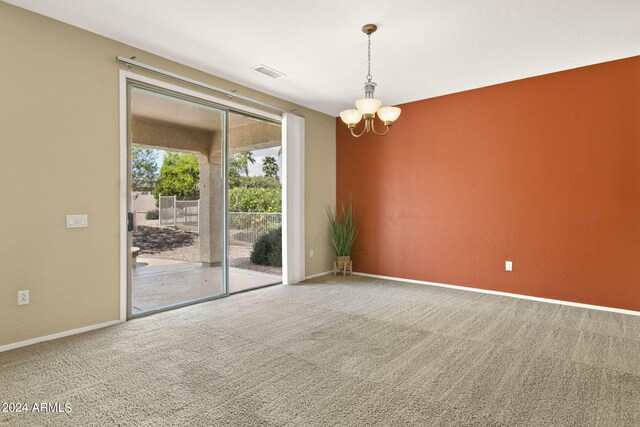 carpeted empty room with a chandelier