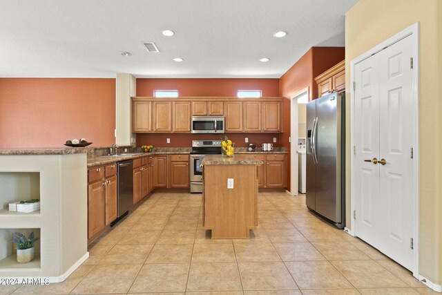 kitchen with light tile patterned floors, sink, stainless steel appliances, and a kitchen island