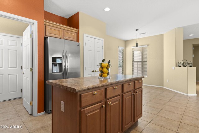 kitchen featuring light tile patterned flooring, stainless steel refrigerator with ice dispenser, pendant lighting, and a kitchen island