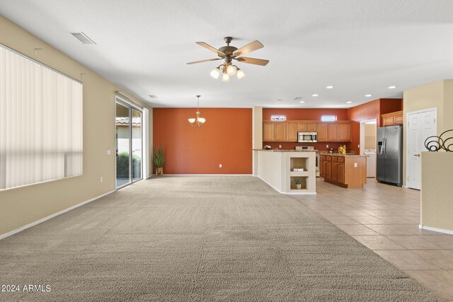 unfurnished living room featuring ceiling fan with notable chandelier and light colored carpet