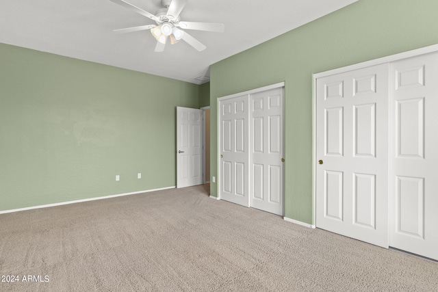 unfurnished bedroom with ceiling fan, two closets, and carpet