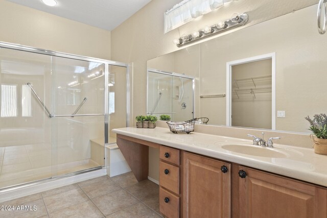 bathroom with tile patterned flooring, a shower with door, and vanity