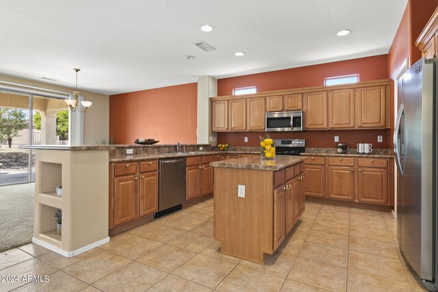 kitchen with decorative light fixtures, appliances with stainless steel finishes, a chandelier, a kitchen island, and light colored carpet