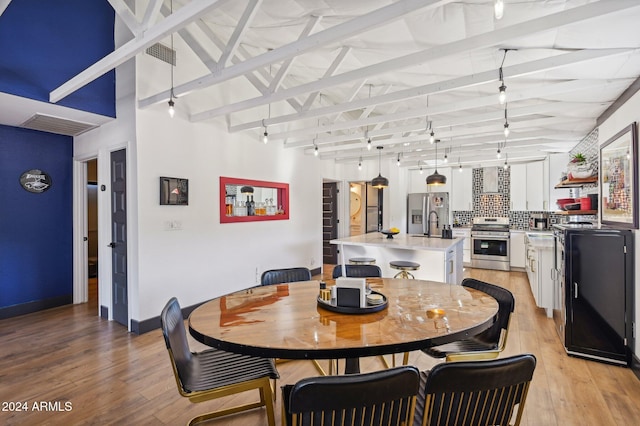 dining room featuring track lighting, light wood-style flooring, and baseboards
