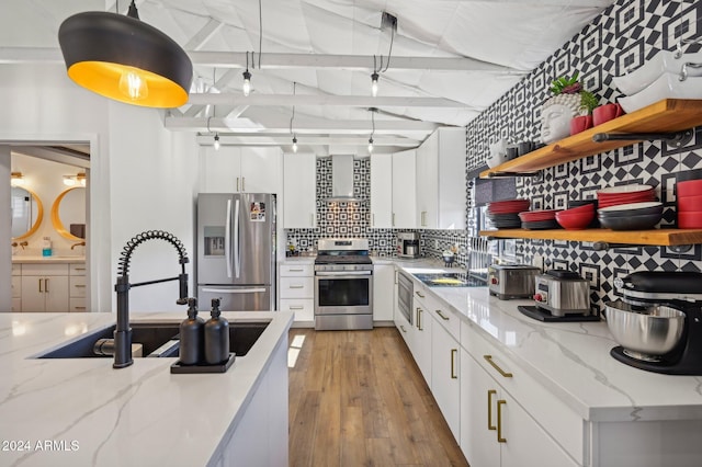 kitchen featuring stainless steel appliances, open shelves, wall chimney exhaust hood, decorative backsplash, and a sink