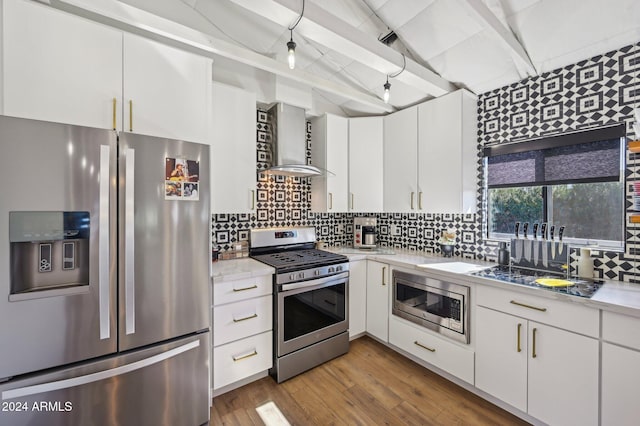 kitchen featuring appliances with stainless steel finishes, wall chimney range hood, beamed ceiling, tasteful backsplash, and light countertops