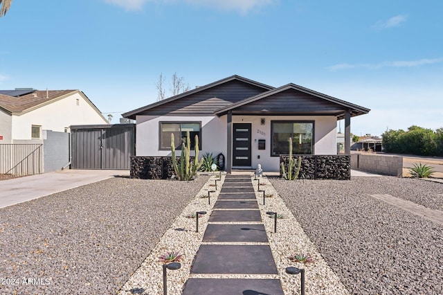 view of front of house featuring fence, a gate, stone siding, and stucco siding