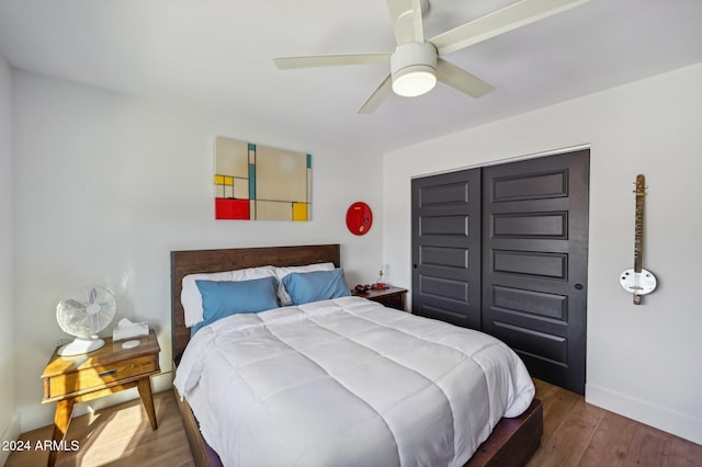 bedroom with wood finished floors, baseboards, ceiling fan, and a closet