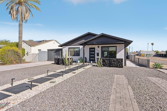 view of front of house featuring a gate, stucco siding, fence, and covered porch
