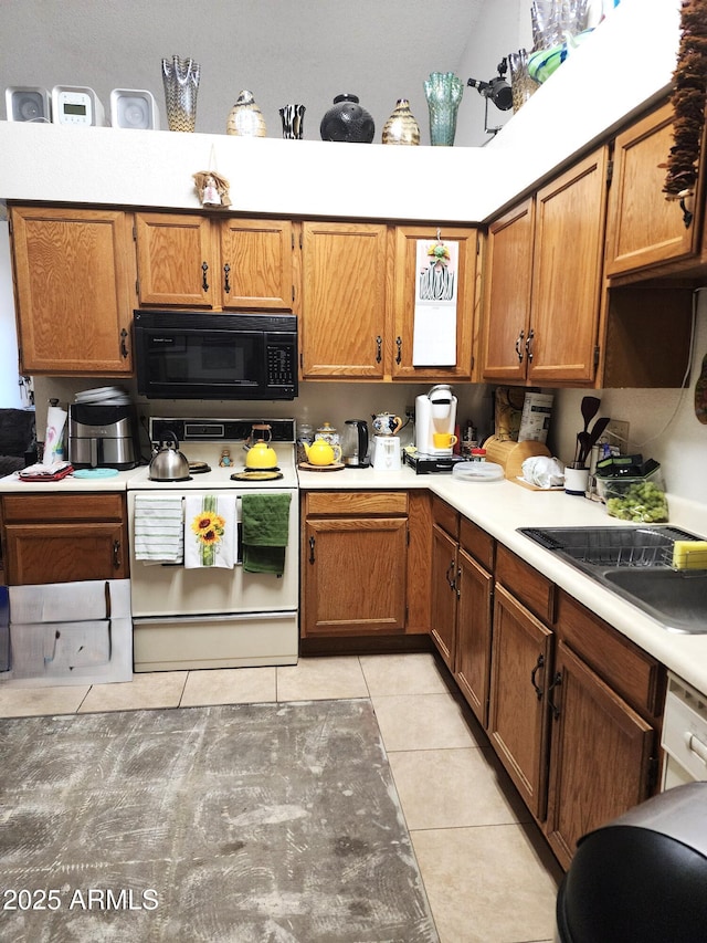 5136 E Evergreen St Unit 1053, Mesa, AZ 85205 - kitchen featuring black microwave, electric range, light tile patterned floors, and brown cabinets