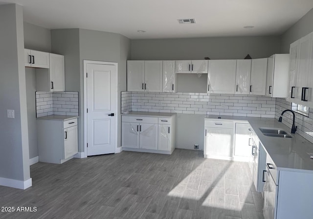 36269 W Highland Ave, Phoenix, AZ 85033 - kitchen with a sink, decorative backsplash, wood finished floors, and white cabinetry