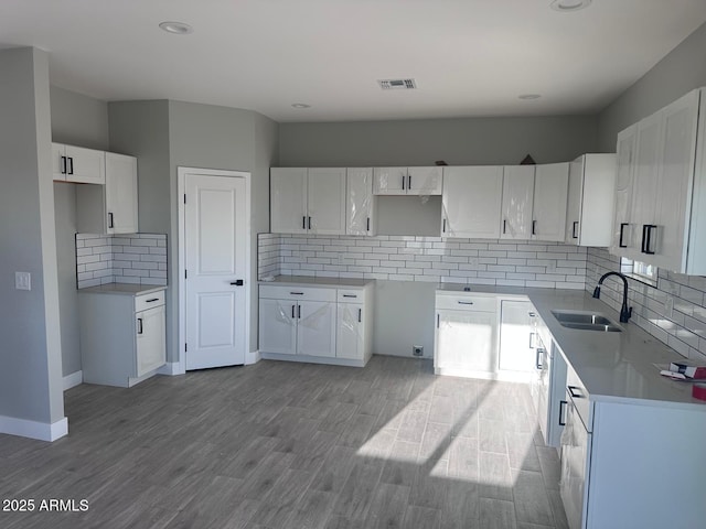 36269 W Highland Ave, Phoenix, AZ 85033 - kitchen with a sink, decorative backsplash, wood finished floors, white cabinets, and recessed lighting