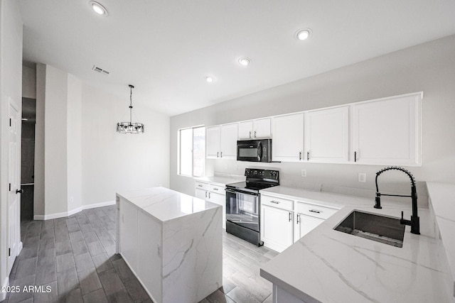 kitchen featuring white cabinetry, decorative light fixtures, a kitchen island, and black appliances