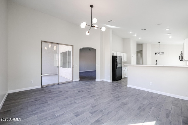 unfurnished living room featuring a notable chandelier, hardwood / wood-style floors, and a high ceiling