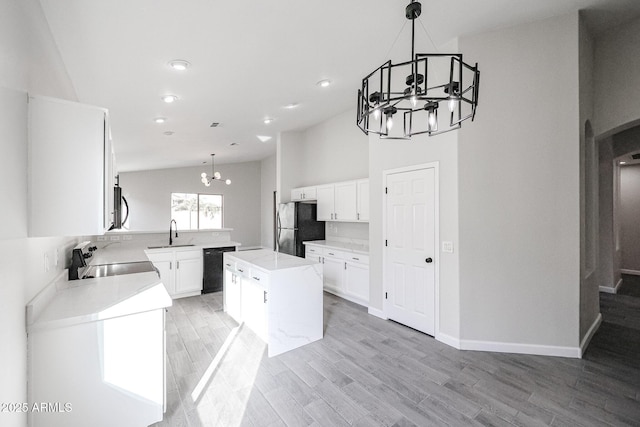 kitchen featuring sink, a center island, a notable chandelier, pendant lighting, and black appliances