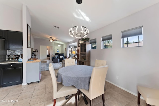 dining room with ceiling fan with notable chandelier, lofted ceiling, and light tile patterned floors