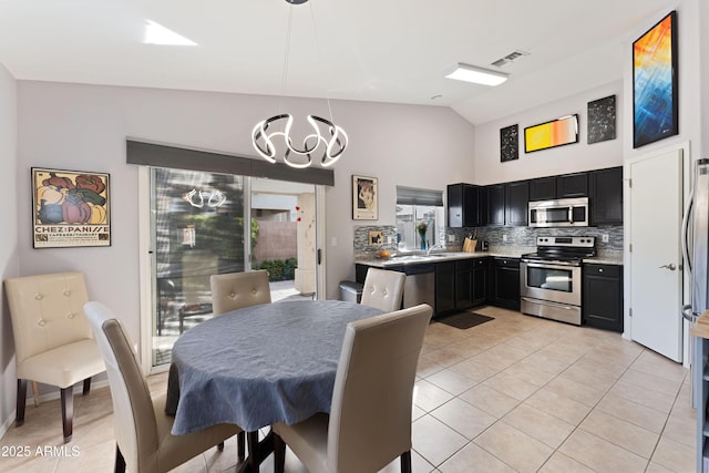 dining room with light tile patterned flooring, lofted ceiling, and a chandelier