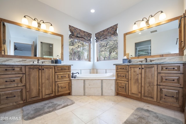 bathroom with two vanities, visible vents, a garden tub, and a sink