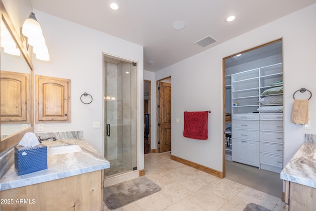 bathroom featuring a spacious closet, vanity, visible vents, and a shower stall