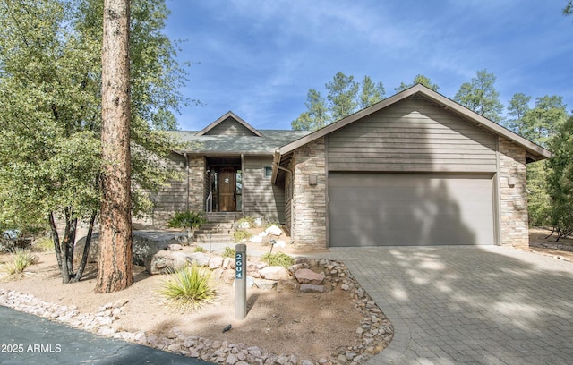 view of front of house with stone siding, decorative driveway, and an attached garage