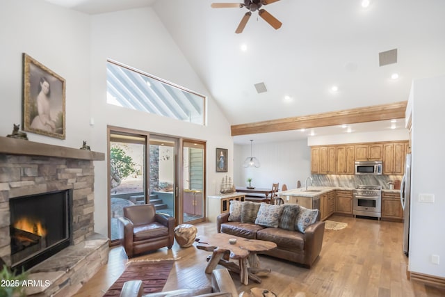 living area featuring light wood-style flooring, visible vents, ceiling fan, and a stone fireplace