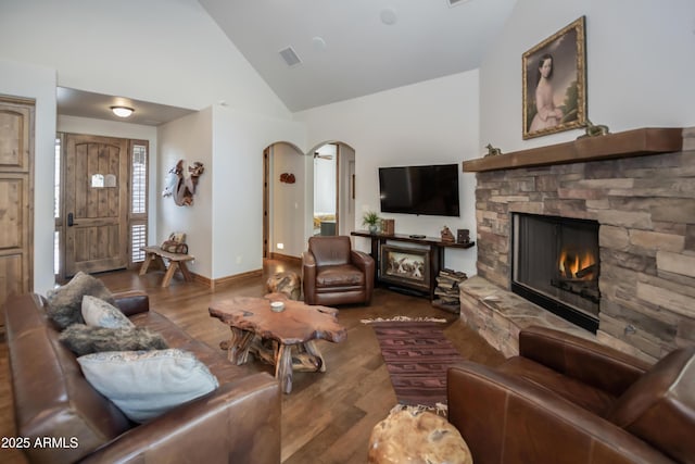 living room featuring arched walkways, a fireplace, wood finished floors, and visible vents