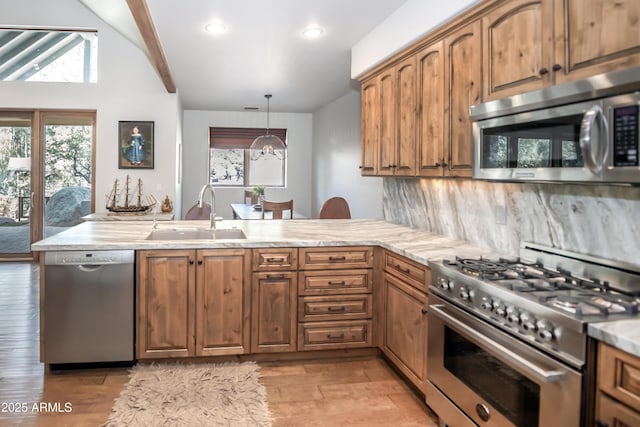kitchen featuring lofted ceiling with beams, a peninsula, a sink, appliances with stainless steel finishes, and brown cabinetry