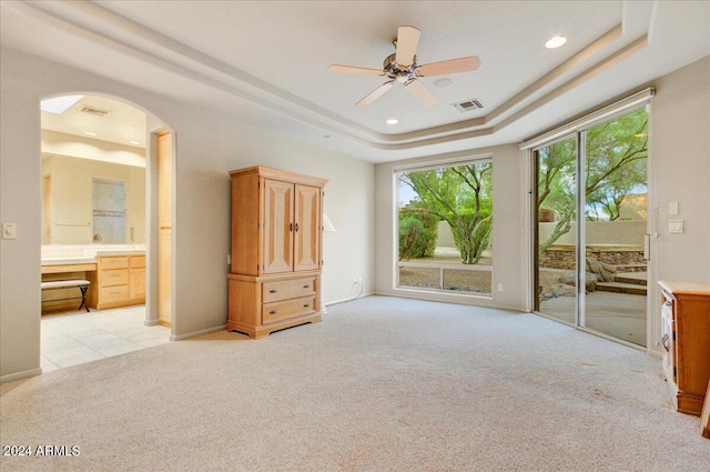 unfurnished bedroom featuring a raised ceiling, access to outside, light carpet, and built in desk