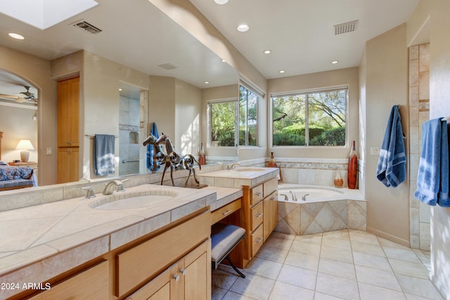 bathroom featuring tile patterned floors, ceiling fan, tiled tub, and vanity