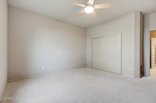 unfurnished bedroom with ceiling fan, light colored carpet, and a closet