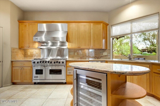 kitchen featuring light stone counters, wall chimney exhaust hood, sink, wine cooler, and double oven range