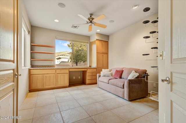 tiled living room with ceiling fan and built in desk