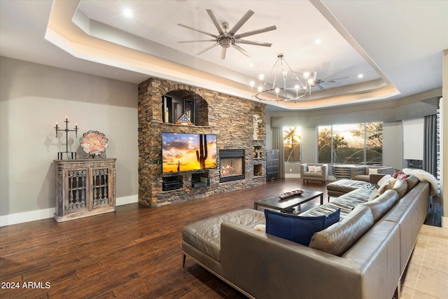 living room with a fireplace, hardwood / wood-style floors, a chandelier, and a raised ceiling