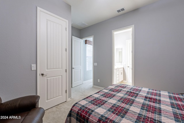 bedroom featuring ensuite bathroom and light carpet