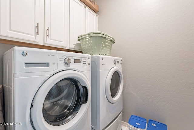 clothes washing area featuring cabinets and washer and dryer