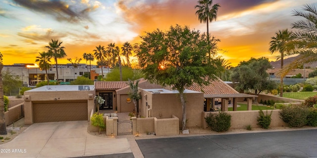 4450 E Camelback Rd Unit 4, Phoenix, AZ 85018 - pueblo revival-style home featuring stucco siding, a gate, an attached garage, a fenced front yard, and driveway