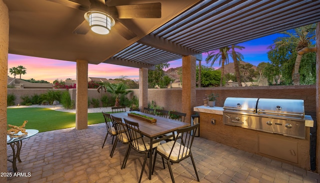4450 E Camelback Rd Unit 4, Phoenix, AZ 85018 - patio terrace at dusk with an outdoor kitchen, a pergola, a fenced backyard, and grilling area