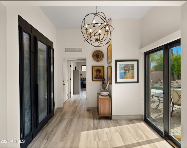 4450 E Camelback Rd Unit 4, Phoenix, AZ 85018 - corridor featuring light wood-style floors, a chandelier, baseboards, a towering ceiling, and visible vents