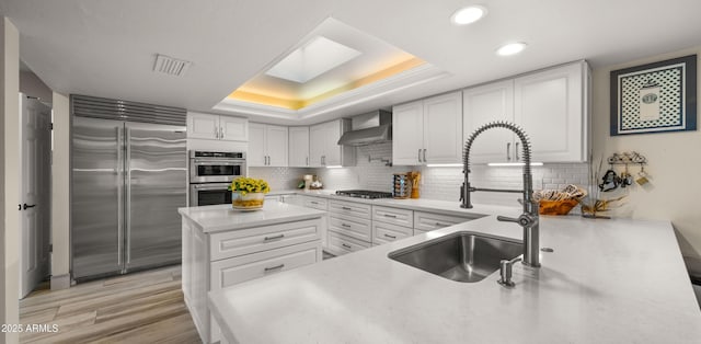 4450 E Camelback Rd Unit 4, Phoenix, AZ 85018 - kitchen with a sink, wall chimney exhaust hood, stainless steel appliances, a tray ceiling, and visible vents