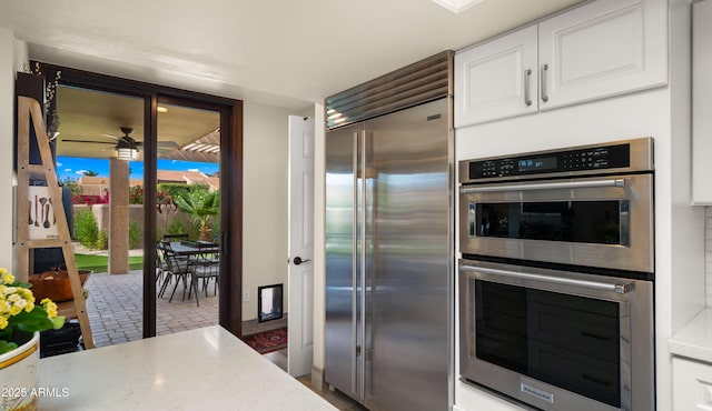 4450 E Camelback Rd Unit 4, Phoenix, AZ 85018 - kitchen with light countertops, appliances with stainless steel finishes, ceiling fan, and white cabinetry