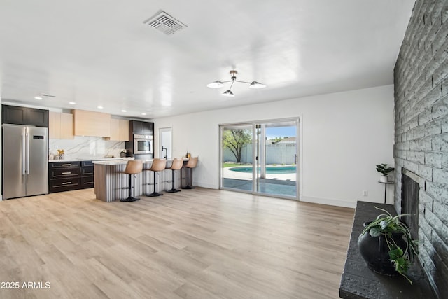 1653 E Palmcroft Dr, Tempe, AZ 85282 - kitchen featuring appliances with stainless steel finishes, light countertops, a kitchen bar, light wood-type flooring, and baseboards