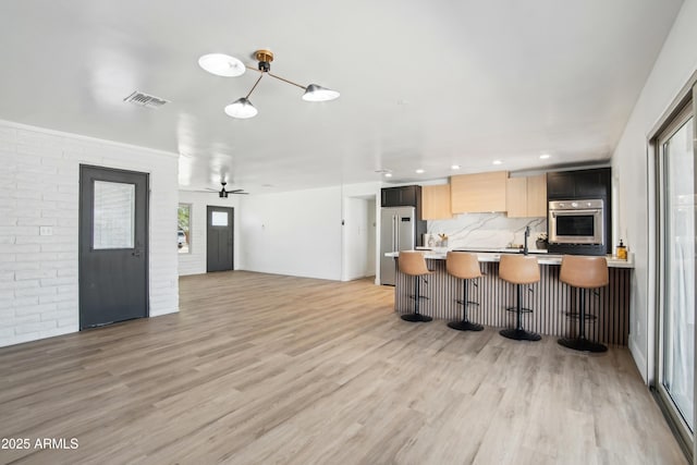 1653 E Palmcroft Dr, Tempe, AZ 85282 - kitchen with appliances with stainless steel finishes, light countertops, light wood finished floors, a kitchen bar, and healthy amount of natural light