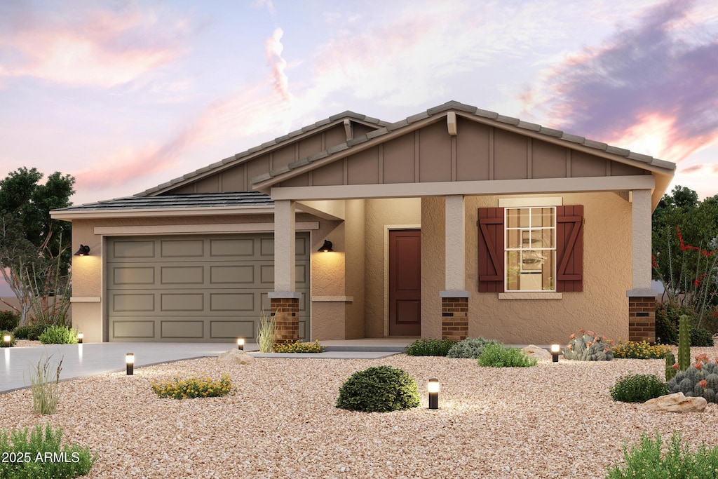 view of front of home featuring brick siding, a garage, driveway, and stucco siding