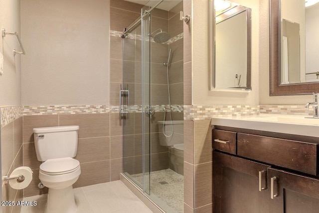 bathroom with walk in shower, toilet, tile walls, vanity, and tile patterned flooring