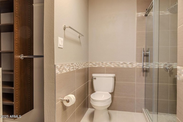 bathroom with toilet, a shower with door, and tile walls