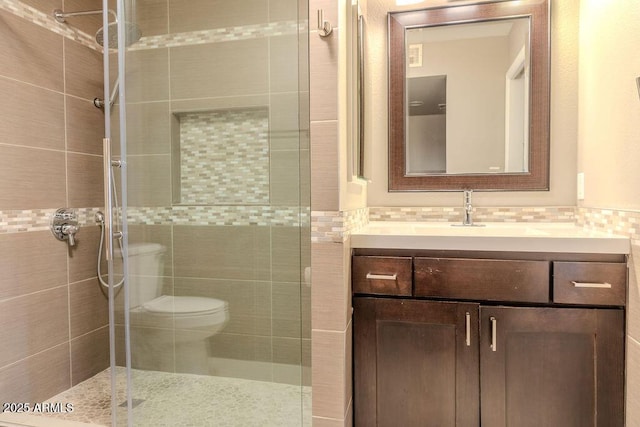 bathroom with tiled shower, vanity, and toilet