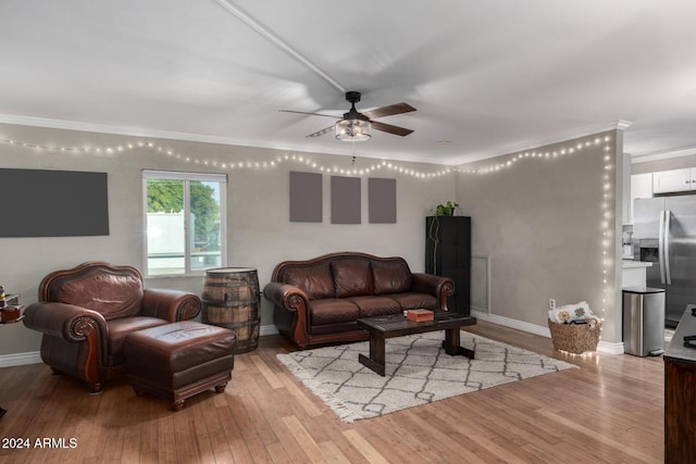 living room featuring ceiling fan, light wood-type flooring, and crown molding