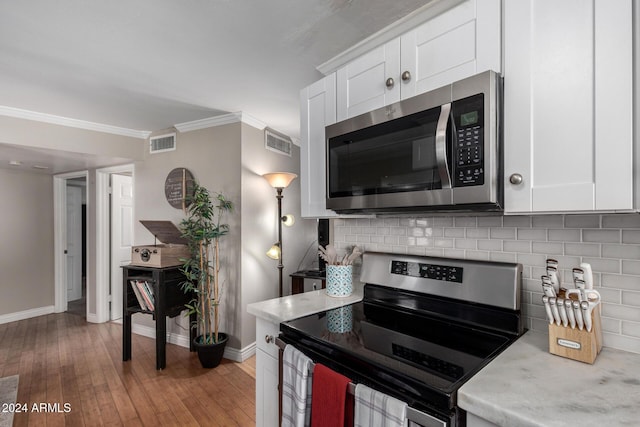 kitchen featuring backsplash, white cabinets, light wood-type flooring, ornamental molding, and stainless steel appliances